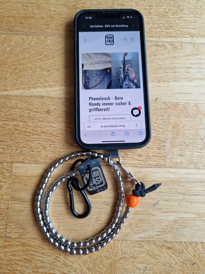 Silberne Original Phoneleash, luxus Handykette mit Edelstahl-Perlen und elastischem Band für sicheren, stilvollen Smartphone-Gebrauch. In Deutschland gefertigt, bietet sie Langlebigkeit und ein dezentes Design mit einer Friedensbotschaft durch ein handgestanztes Peace-Zeichen und Herz.